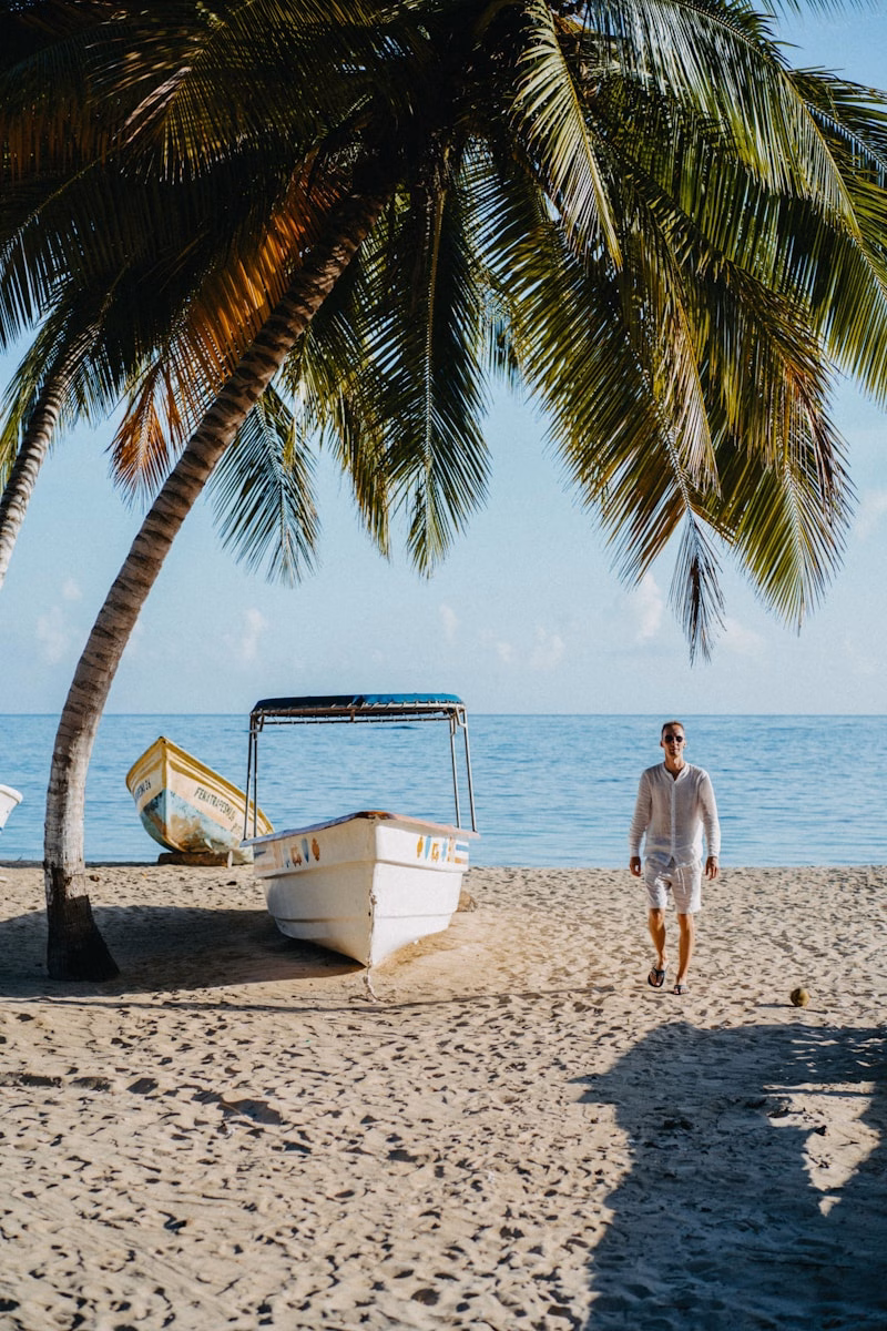 A man standing on a beach next to a boat
